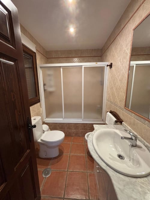Modern bathroom with shower enclosure, sink, and toilet at Hotel Mulhacén Trevélez in Granada, Spain