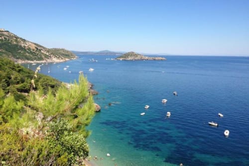 Pittoresca caletta costiera toscana vicino a Casale Artemisia a Capalbio con acque turchesi e barche ormeggiate