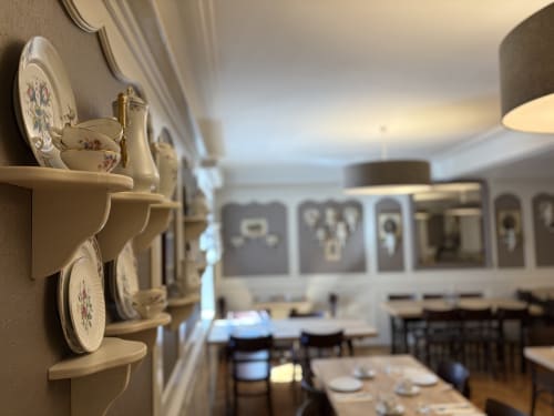 Salle à manger de l'Hôtel de l'Ange avec assiettes décoratives sur étagères murales et couverts élégants