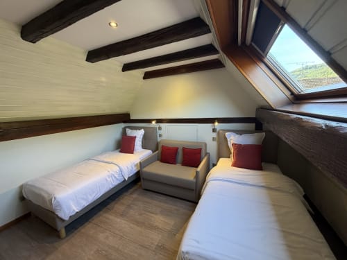 Chambre mansardée douillette à l'Hôtel de l'Ange à Niedermorschwihr avec lits jumeaux, poutres apparentes et fenêtres de toit