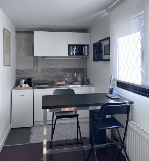 Cocina moderna y comedor en La Porte Rouge, Roubaix con cocineta equipada, mesa negra y vistas a la ciudad