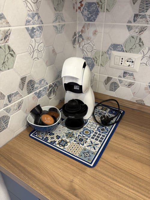 White Delonghi coffee maker with capsule cup on patterned mat in Catalogna10 hotel apartment, Alghero