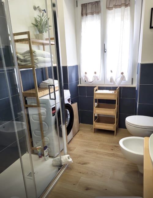 Modern bathroom with shower, toilet, sink, wooden storage and bunk beds in Catalogna10 hotel apartment, Alghero Italy