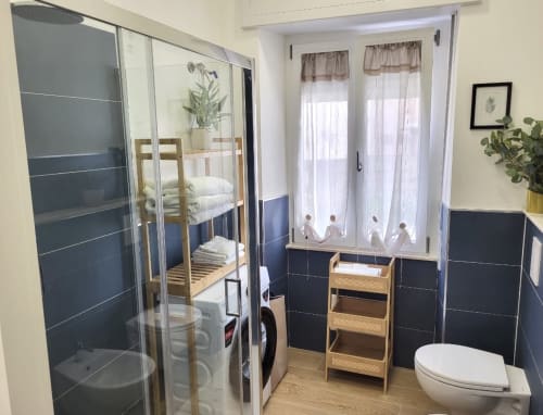 Modern bathroom with shower, toilet, bidet, wooden storage shelves, and bunk bed visible in Catalogna10 Rooms apartment in