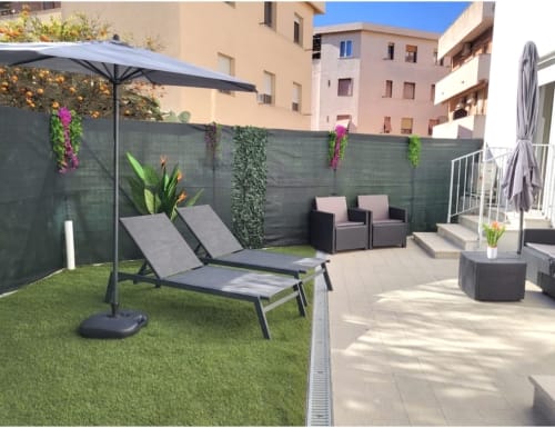 Modern terrace at Catalogna10 in Alghero with loungers, umbrellas, artificial grass, climbing plants, and patio seating