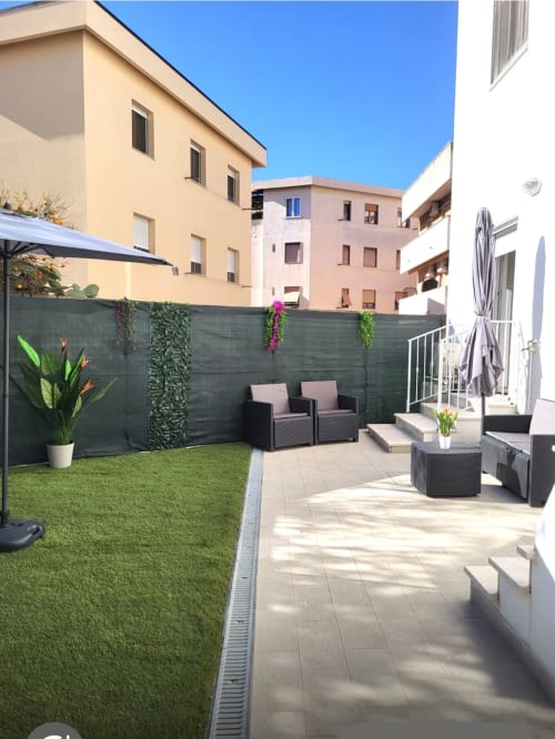 Modern apartment terrace at Catalogna10 Rooms in Alghero with artificial grass, lounge seating, and shaded garden patio area