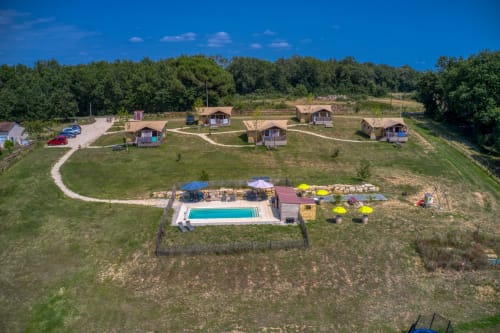 Vue aérienne du resort de glamping Home Sweet Lodge avec piscine, cabanes en bois et jardins luxuriants en Aquitaine