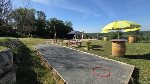 Glamping-area bij Home Sweet Lodge met pétanquebaan, gele parasols en houten vaten in Aquitanië