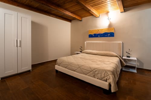 Camera da letto moderna con letto color crema, travi in legno a vista, armadio bianco e pavimento in legno presso Stone House Gebel el Son