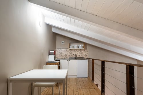 Moderna cucina mansardata nella Stone House cottage a Gebel el Son, Novi Velia, con mobili bianchi e tavolo da pranzo