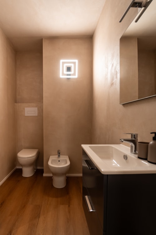 Bagno moderno della Stone House Gebel el Son con toilette, bidet, lavabo bianco e applique neon a Novi Velia