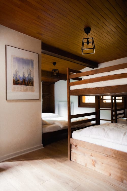Rustic bedroom at Chalet Viñales in Les Houches with wooden bunk beds, beamed ceiling, and framed artwork