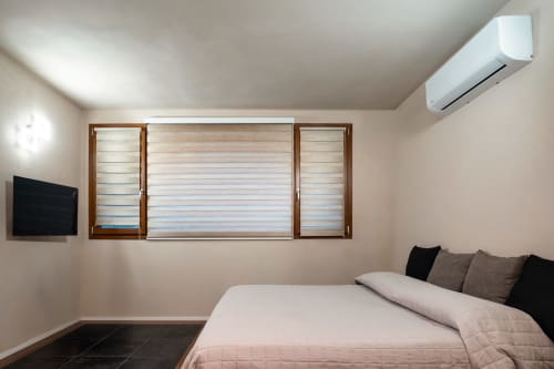 Moderna camera matrimoniale a Stone House Gebel el Son con letto queen, TV, aria condizionata e finestra con persiane in legno