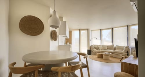 Modern apartment living space at Casa Redonda Aroeira with round dining table, seating area, and natural light from large