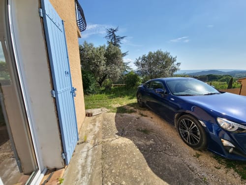 Voiture de sport bleue garée à l'appartement Smooth Luberon à Villars, Provence, avec vue sur les montagnes et oliviers
