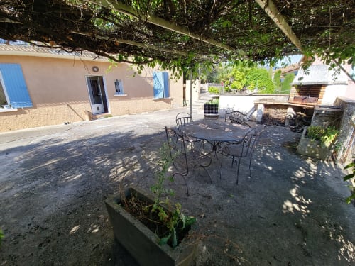Cour ombragée avec table de salle à manger et chaises au Smooth Luberon à Villars, Provence, entourée de lierre et d'architecture traditionnelle