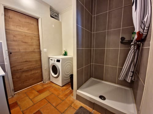 Buanderie moderne à Smooth Luberon avec lave-linge, cabine de douche et carrelage en terre cuite