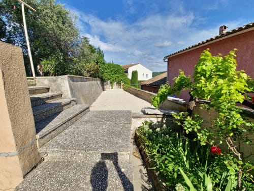Chemin pavé menant aux bâtisses provençales de l'hôtel Smooth Luberon à Villars, France, avec vue sur les montagnes