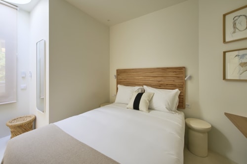 Modern bedroom at Casa Redonda Aroeira with wooden headboard, white bedding, ensuite bathroom, and pool view in Portugal