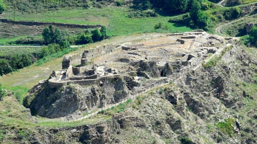 Aerial view of ancient Roman ruins at Hotel Lo Paller in València d'Àneu, Spain, surrounded by green hillside landscape.