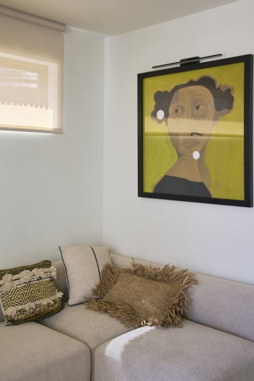 Estúdio da Casa Redonda Aroeira com obra de arte amarela acima do sofá bege e almofadas decorativas