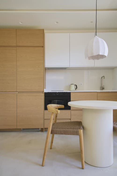 Cozinha e sala de jantar modernas no estúdio Casa Redonda Aroeira com marcenaria em madeira, luminária de vidro branco e mesa redonda