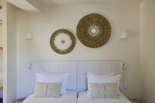 Modern bedroom with twin beds, woven wall decor, and white bedding at Casa Redonda Aroeira, Portugal
