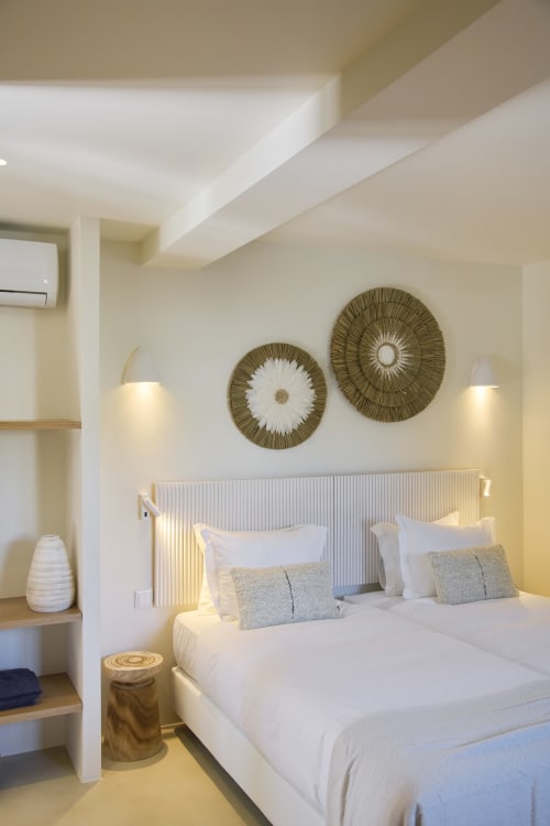 Modern bedroom at Casa Redonda Aroeira with twin beds, white linens, decorative wall art, and garden view lighting