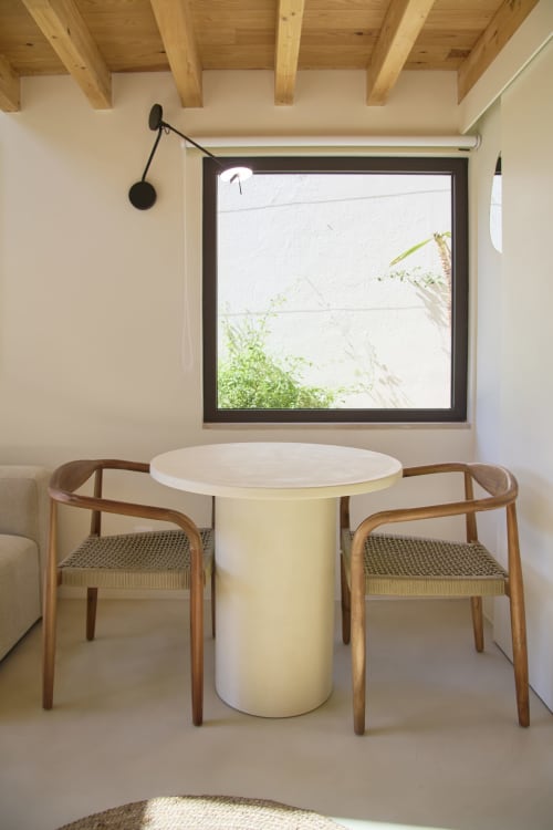 Modern dining area with round table, wooden chairs, and garden view at Casa Redonda Aroeira boutique hotel in Portugal