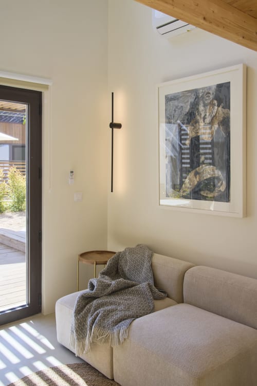Modern living area with beige armchair, throw blanket, framed artwork, and skylight at Casa Redonda Aroeira