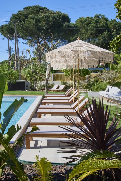 Casa Redonda Aroeira villa pool area with wooden deck, fringe umbrella, and lush tropical garden in Portugal