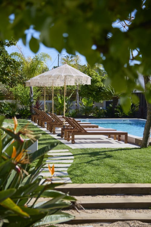 Casa Redonda Aroeira villa poolside with lounge chairs, white umbrella, tropical gardens, and blue swimming pool in Portugal