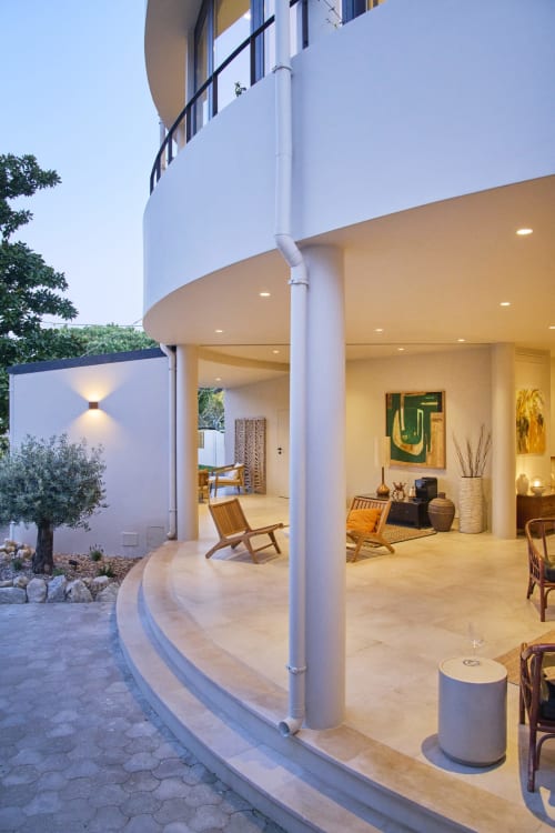 Casa Redonda Aroeira villa courtyard with curved modern architecture, illuminated covered patio, wooden seating, and