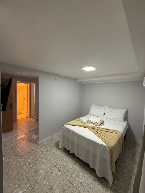 Quarto moderno no Downtown Rooftop 375 em Macaé com cama queen, roupa de cama branca e acesso a casa de banho privada