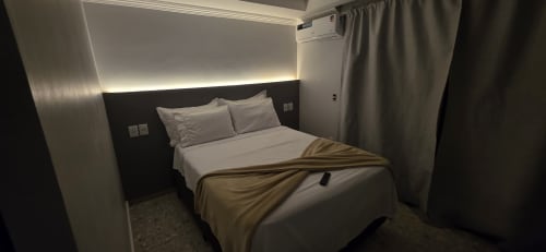 Quarto moderno no Downtown Rooftop 375 em Macaé com cama queen, iluminação ambiente, ar condicionado e vista para o mar