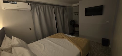 Quarto de hotel moderno no Downtown Rooftop 375 em Macaé com cama, TV de ecrã plano, ar condicionado e ventilador de piso