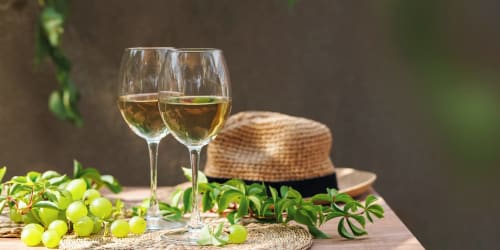 Two glasses of white wine with fresh grapes and straw hat at Casa Rural Finca El Olivar