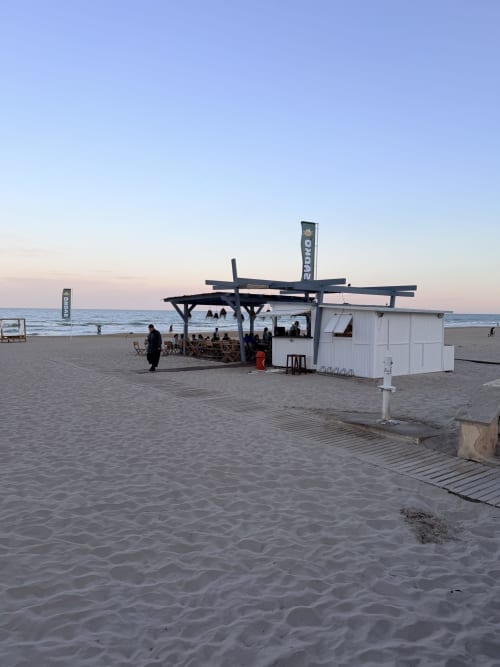Beach bar setup at El Chalecito de Alicante with wooden pergola, white cabana, and sea view at dusk