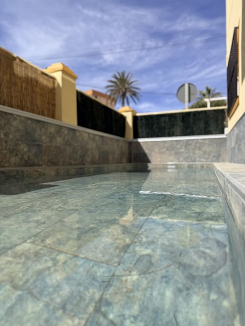 Modern swimming pool courtyard at El Chalecito de Alicante hotel with stone walls and yellow architecture under blue sky