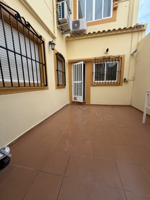 Patio terracotta at El Chalecito de Alicante hotel with barred windows and yellow walls