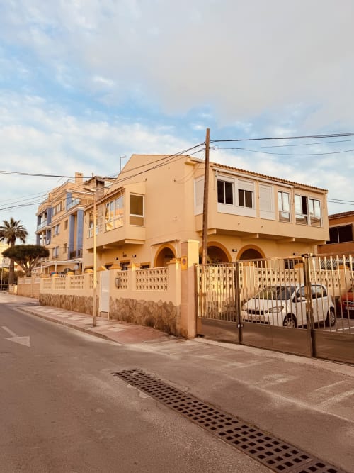 Fachada exterior del hotel El Chalecito de Alicante con tonos melocotón, entrada arqueada y puerta metálica en Alicante, España