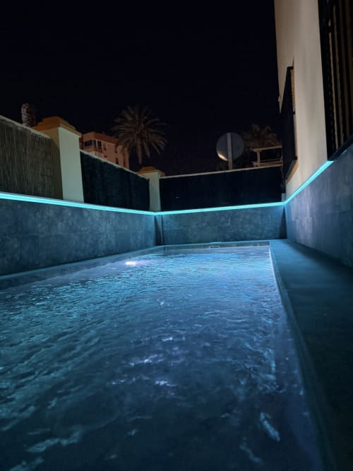 Modern rooftop pool at El Chalecito de Alicante hotel with glowing turquoise water and nighttime city views