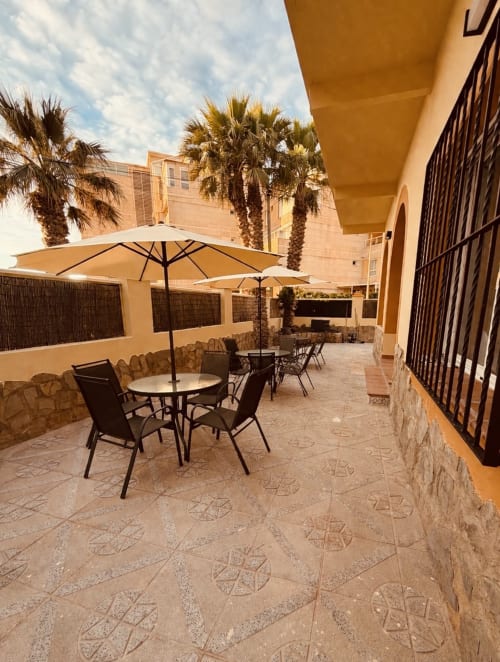El Chalecito de Alicante courtyard with umbrella tables, palm trees, and tiled terrace