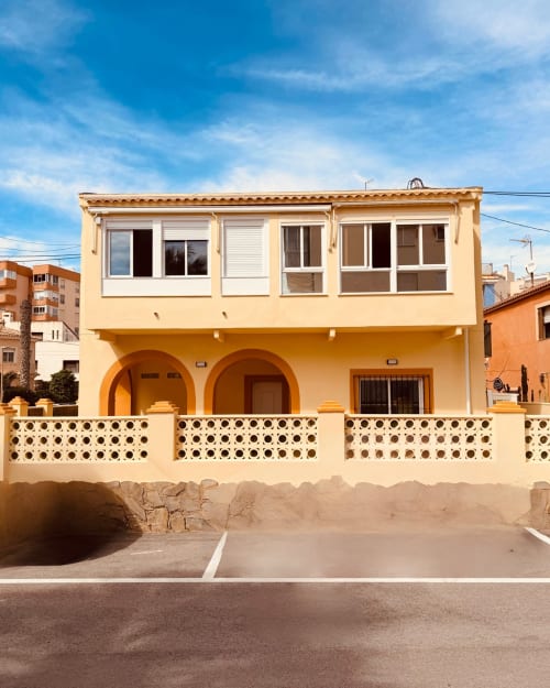El Chalecito de Alicante, un encantador hotel frente al mar con fachada amarilla, pórtico arqueado y reja decorativa