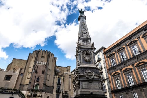 Monumento storico nella piazza napoletana con edifici colorati, ideale per gli ospiti del Dreams & Colors B&B alla scoperta della cultura italiana