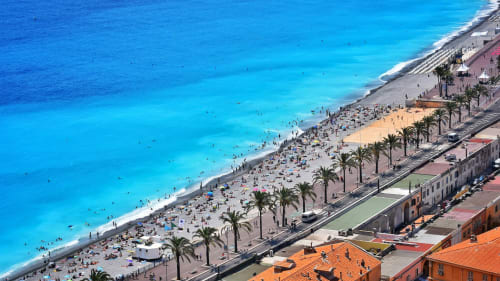 Vista aérea de la playa de Alicante con aguas turquesas del Mediterráneo, arena blanca, palmeras y edificios frente al mar