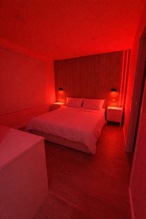 Red neon-lit modern bedroom at El Chalecito de Alicante hotel with bed, nightstands, and ambient lighting