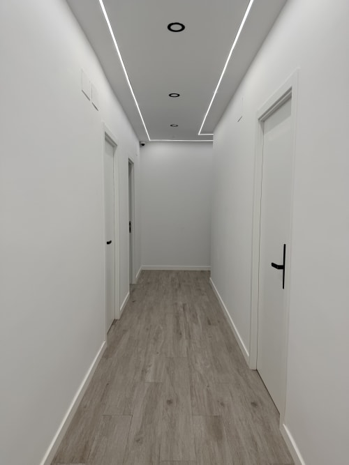 Modern hallway at El Chalecito de Alicante with white walls, wood flooring, and LED ceiling lights
