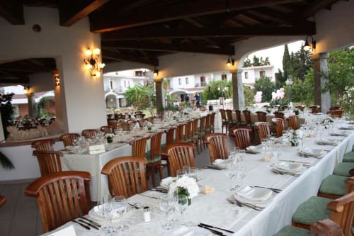 Elegante tavolo da pranzo presso Hotel Ristorante Domu Incantada a Muravera con sedie in legno, biancheria bianca e giardino