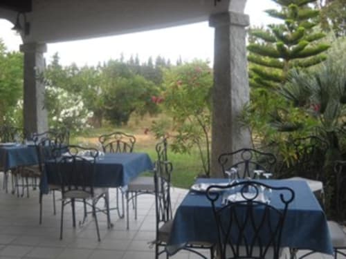 Area ristorazione esterna dell'Hotel Ristorante Domu Incantada a Muravera con tavoli in blu e vista sulla foresta
